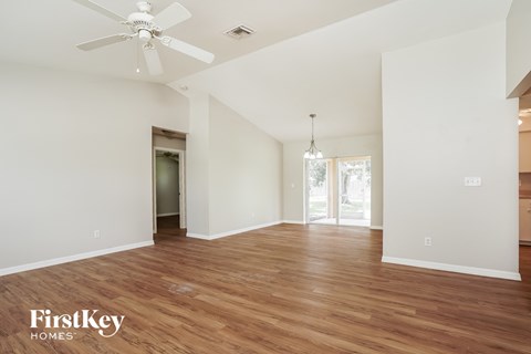 a living room with white walls and wood flooring and a ceiling fan
