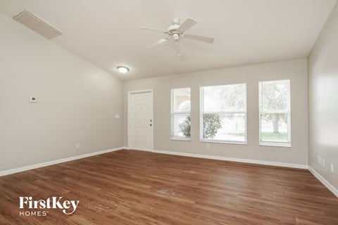the spacious living room with wood flooring and a ceiling fan