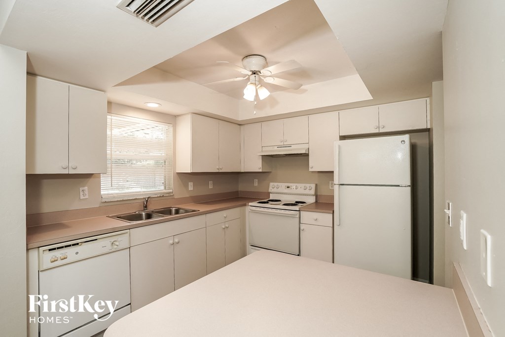 a white kitchen with white appliances and a ceiling fan