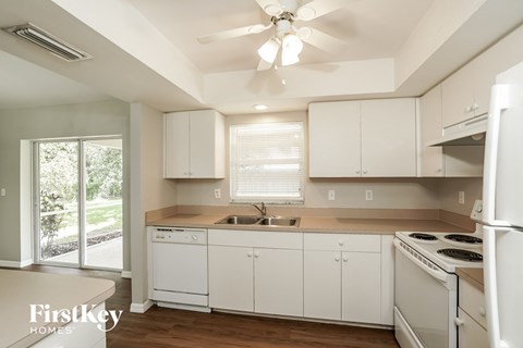 a kitchen with white cabinets and white appliances and a ceiling fan