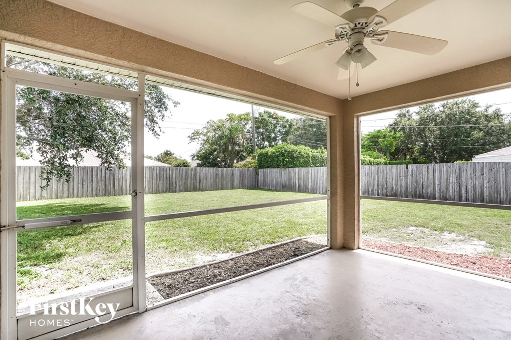 a view of the backyard from a conservatory with a ceiling fan