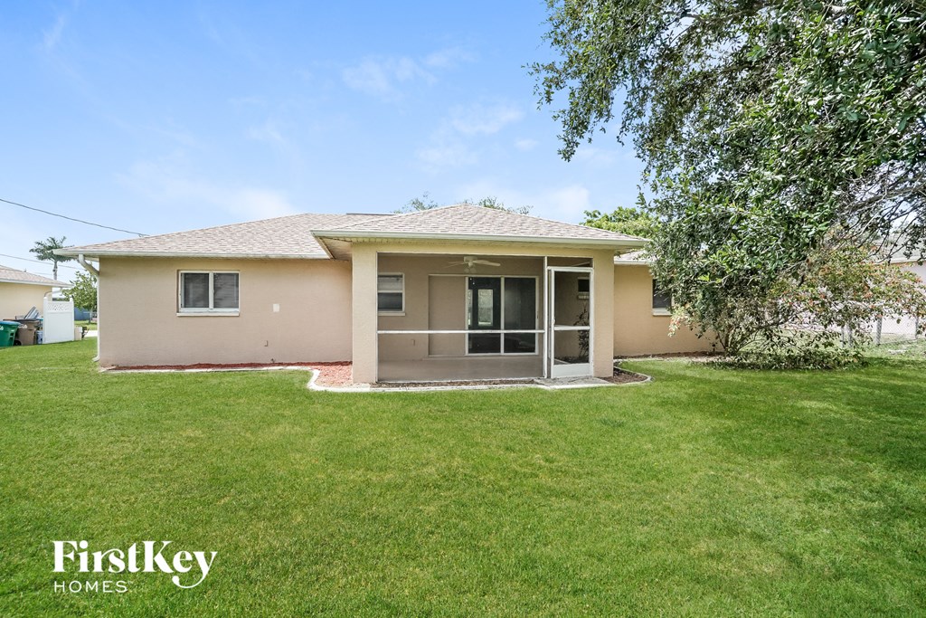 a small beige house with a lawn and a tree