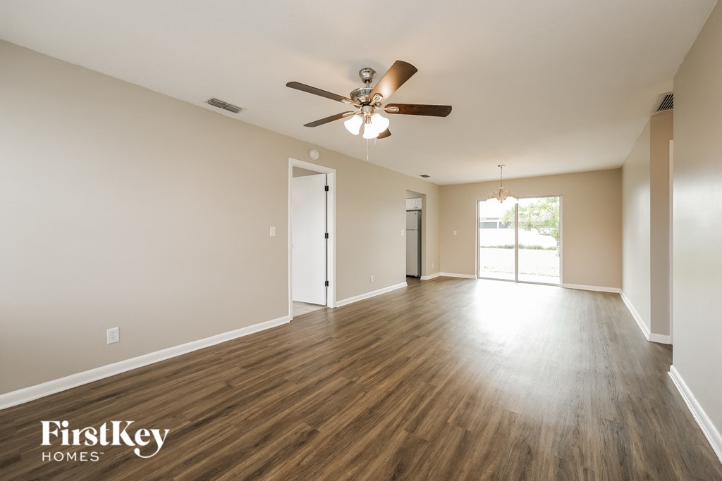an empty living room with wood floors and a ceiling fan