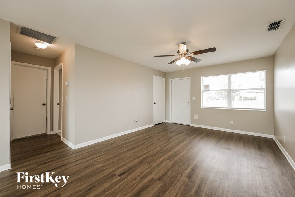 an empty living room with wood floors and a ceiling fan