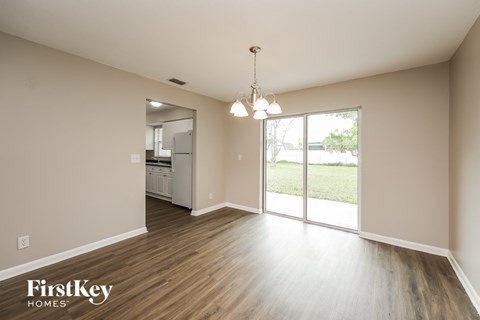 an empty living room with a sliding glass door to the kitchen