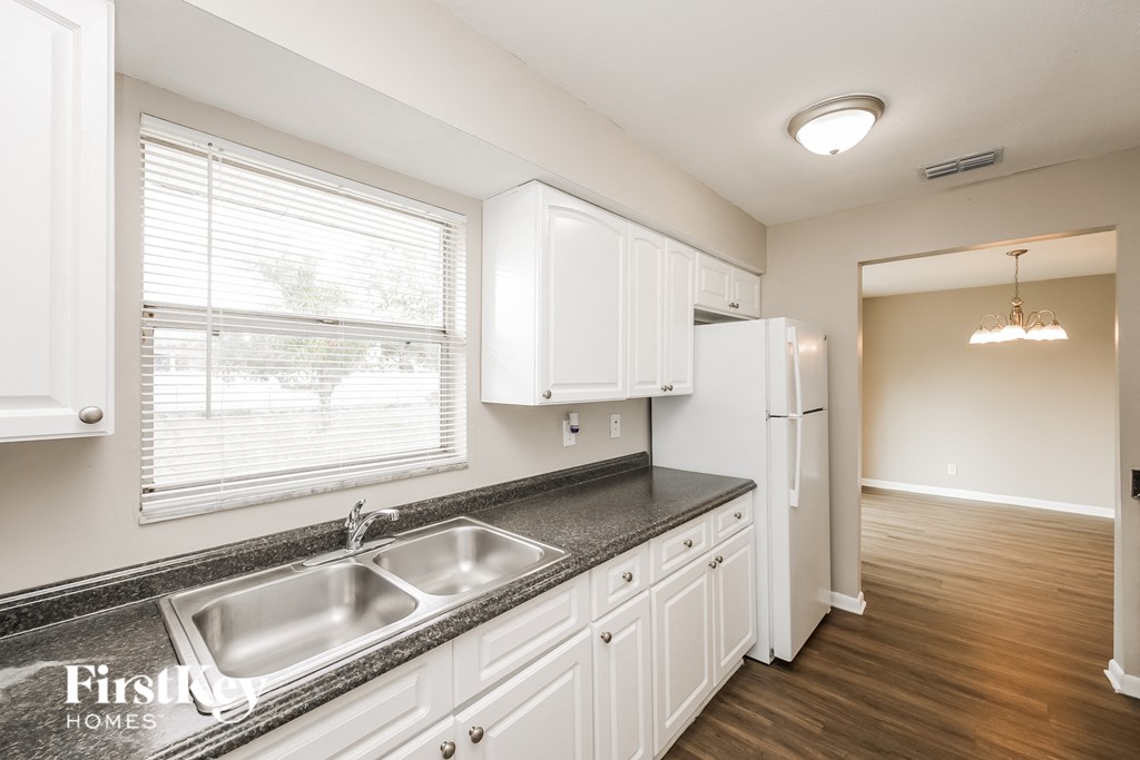 a kitchen with white cabinets and a sink and a window