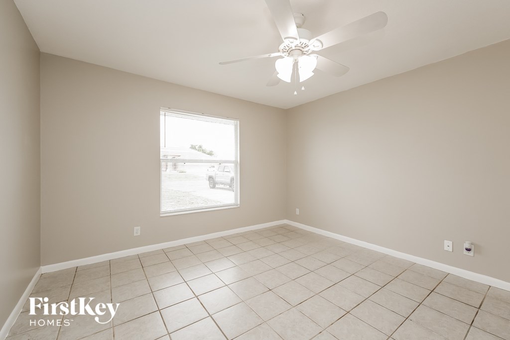 an empty living room with a ceiling fan and a window