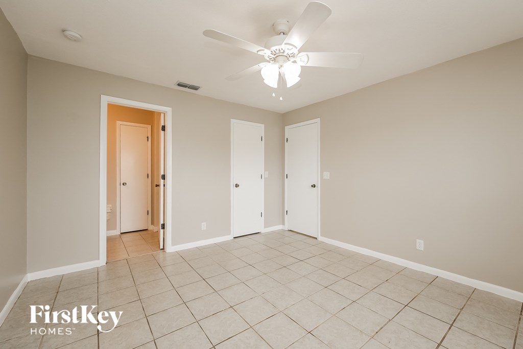 a empty living room with a ceiling fan and tiled floors