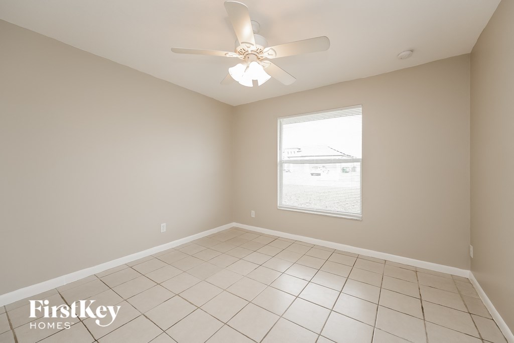 an empty room with a ceiling fan and a window