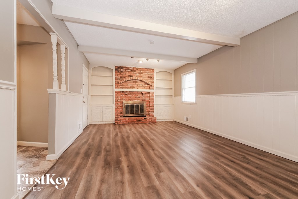 an empty living room with a fireplace and wooden floors