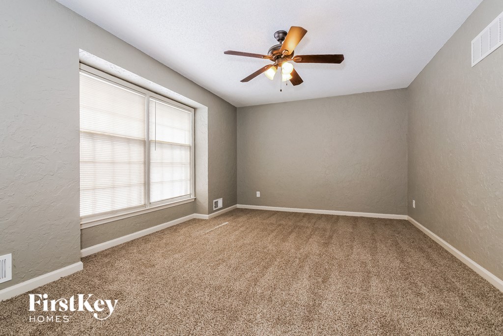 an empty living room with a ceiling fan and a window