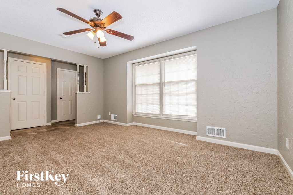 an empty living room with a ceiling fan and a window