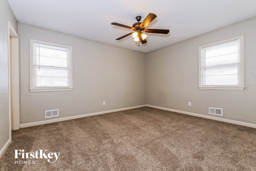 the living room of a home with carpet and a ceiling fan