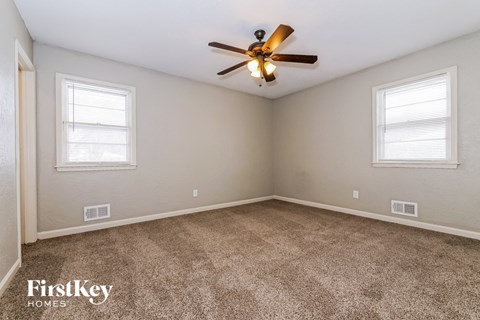 the living room of a home with carpet and a ceiling fan