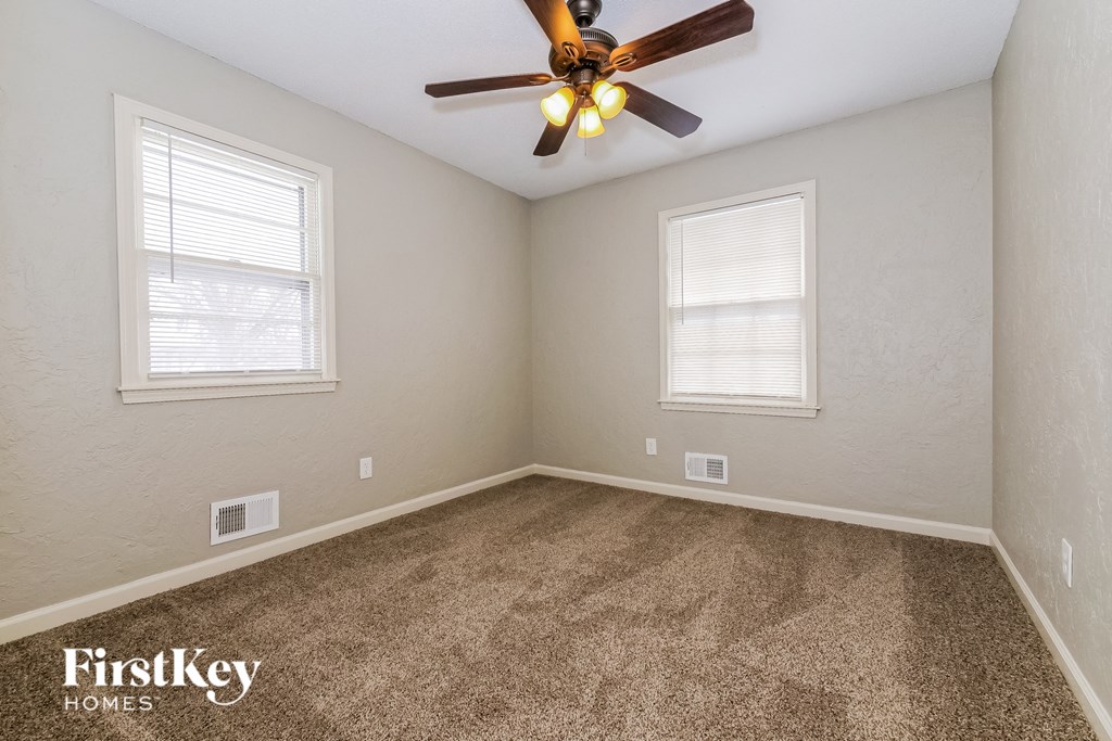 the living room of a home with carpet and a ceiling fan