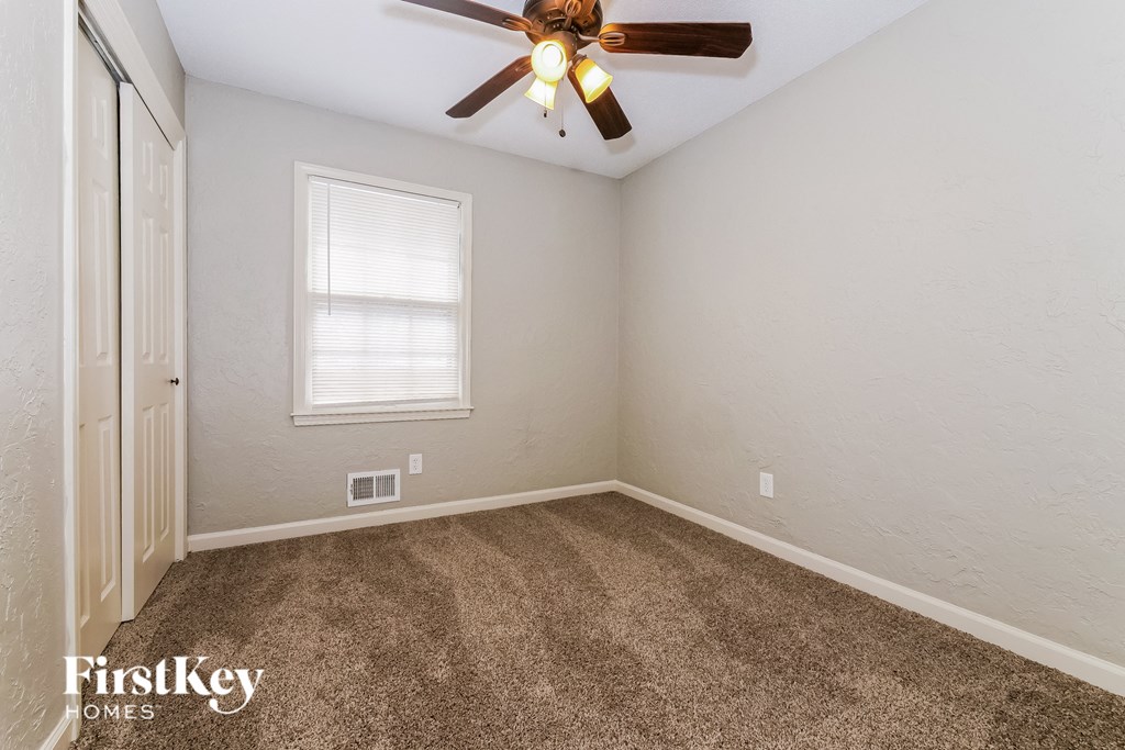 the bedroom of our studio apartment atrium with ceiling fan and carpet