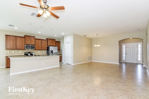 A spacious kitchen and living room with a ceiling fan and lighting fixtures.