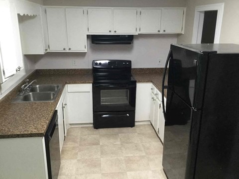A black refrigerator is on the right side of the kitchen.