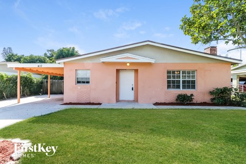 A pink house with a white door and windows is for sale.