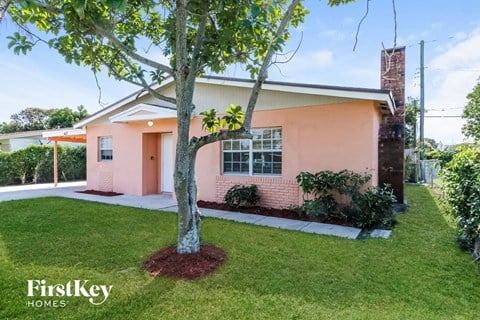A pink house with a tree in front of it.