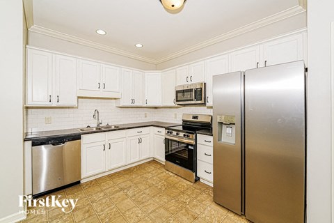 A kitchen with white cabinets and a stainless steel refrigerator.