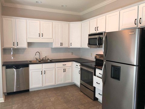 A kitchen with white cabinets and a black countertop.