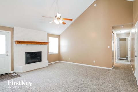 A spacious room with a fireplace and a ceiling fan.