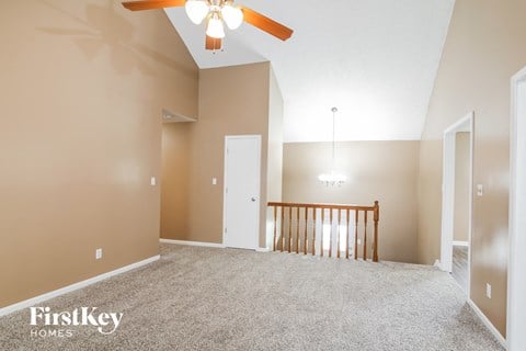 A spacious room with a ceiling fan and a wooden railing.