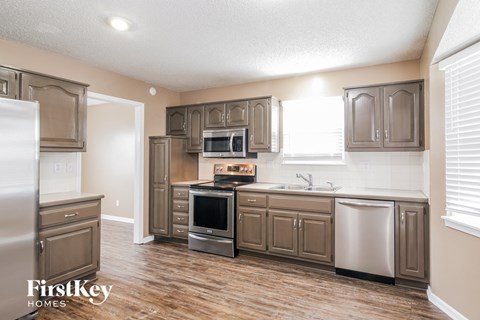 A kitchen with wooden floors and brown cabinets.
