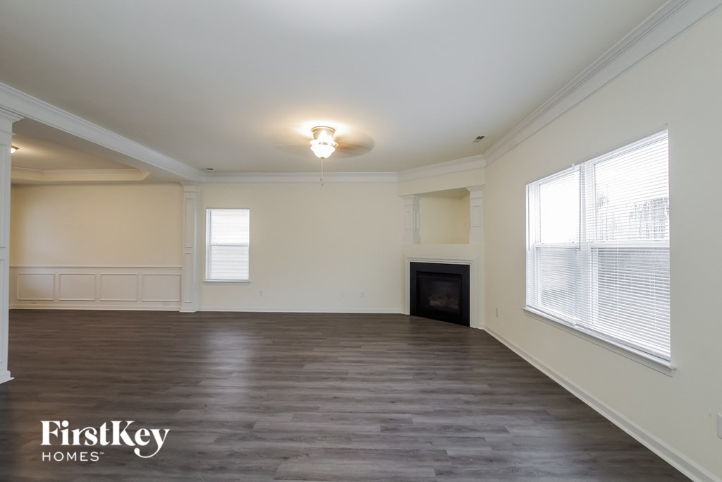 A spacious room with a fireplace and wooden flooring.