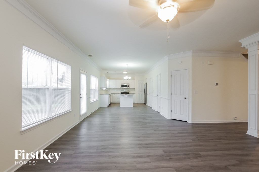 A spacious room with a fan and wooden flooring.