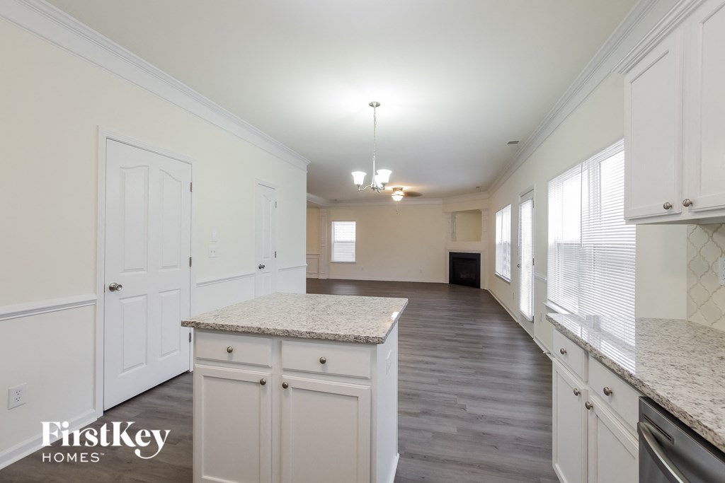 A kitchen with white cabinets and a granite countertop.