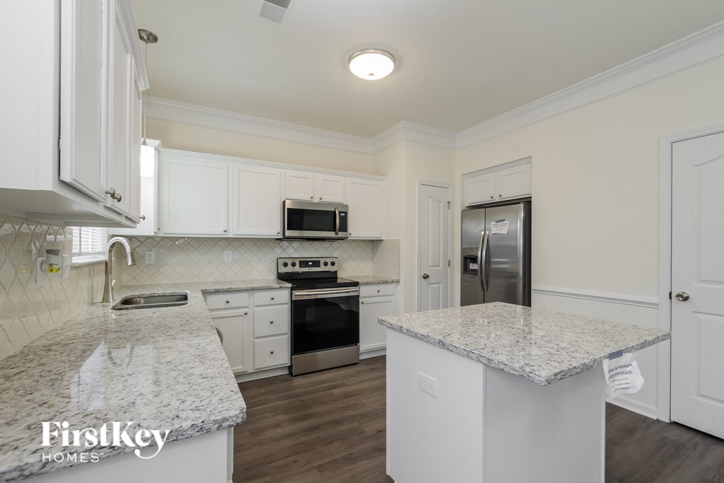 A kitchen with white cabinets and granite countertops.