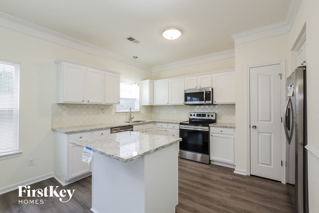 A kitchen with white cabinets and a granite countertop.