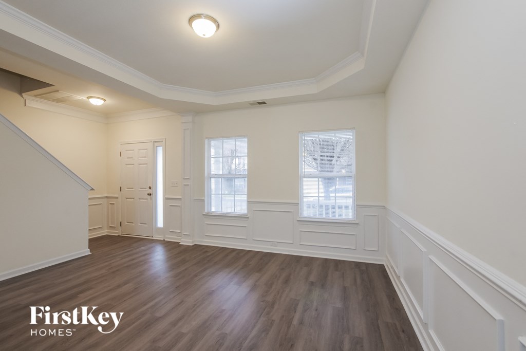 A room with wooden floors and white walls, with a window and a door visible.