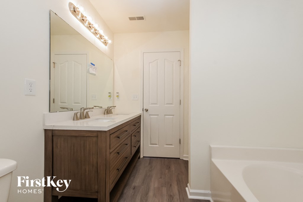 A bathroom with a tub, sink and mirror.