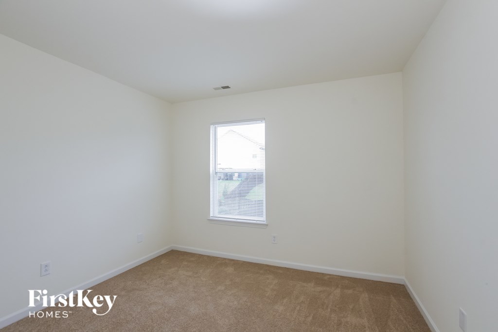 A room with a window and a carpeted floor.