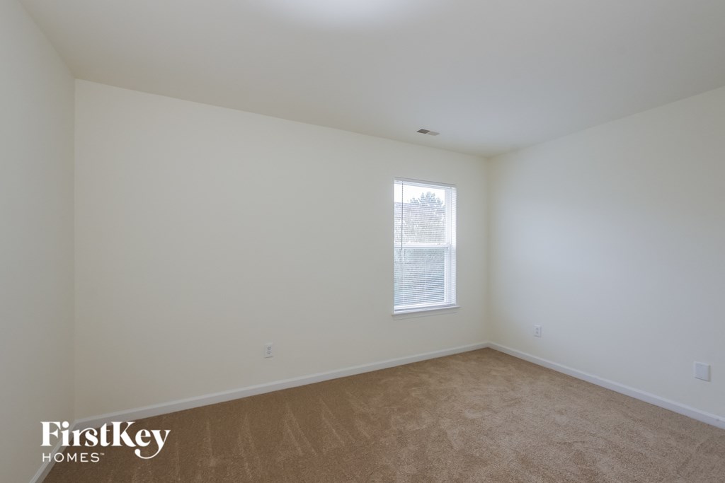 A room with a window and a carpeted floor.