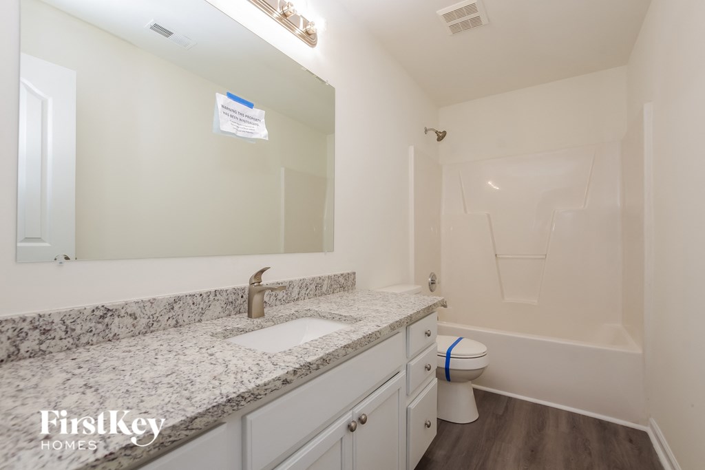 A bathroom with a marble countertop and a toilet in the corner.