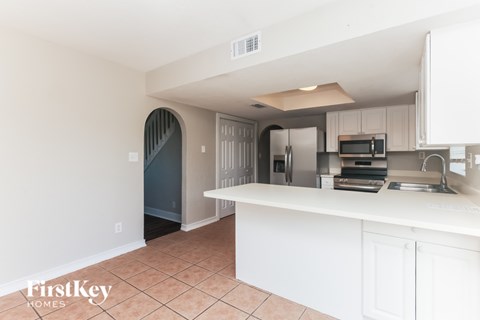 A kitchen with a white counter top and a microwave on it.