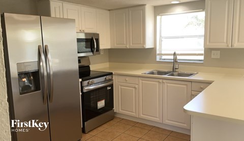 A kitchen with a refrigerator, oven, and sink.
