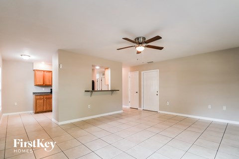 an empty living room with a ceiling fan and tiled floor