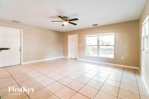an empty living room with a ceiling fan and tiled floors
