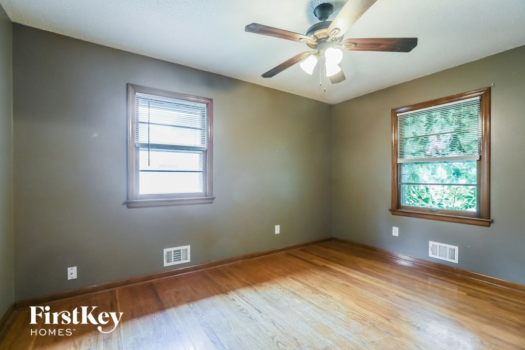an empty room with wood floors and a ceiling fan