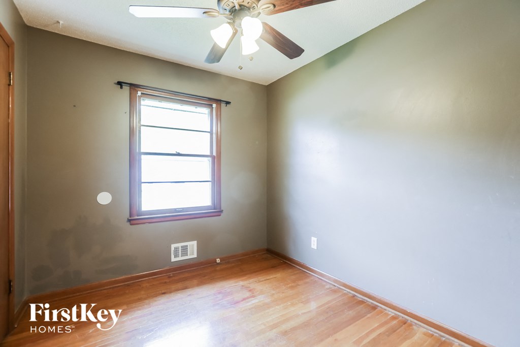 an empty room with a ceiling fan and a window