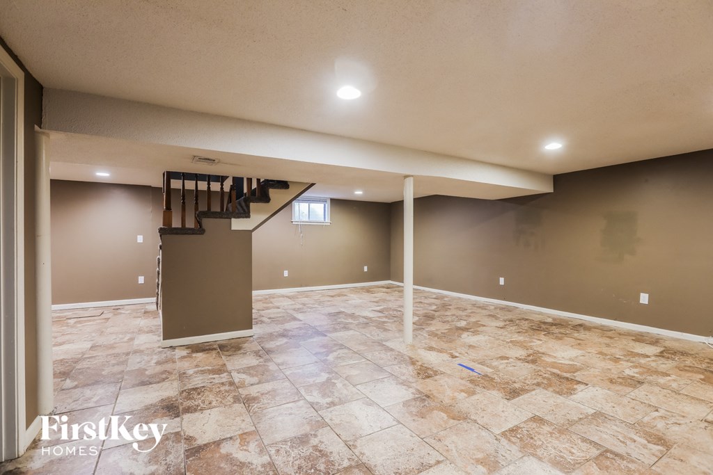a empty basement with a staircase and tile flooring