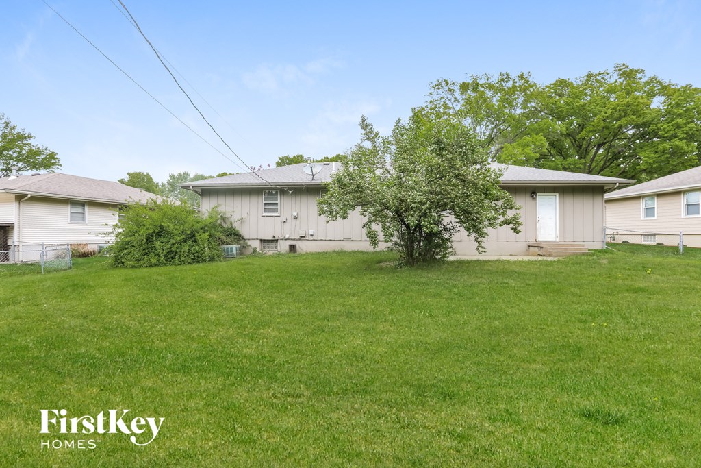 the backyard of a house with a lawn and a tree
