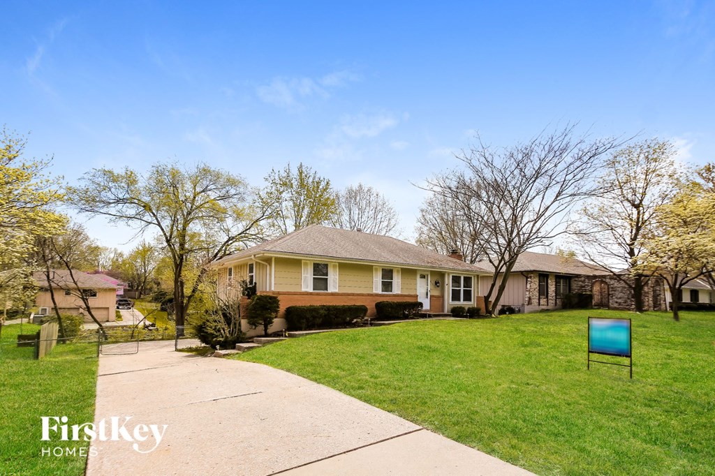 a home with a yard and a blue sign on the sidewalk