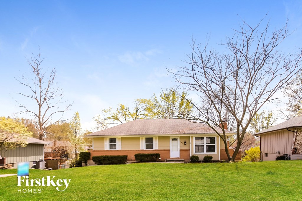 a small yellow house with a green lawn and some trees