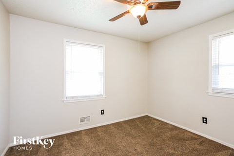 a bedroom with two windows and a ceiling fan